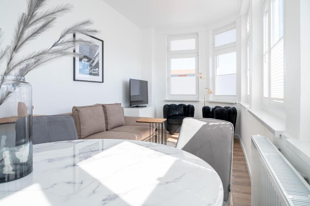 uma sala de estar branca com uma mesa e um sofá em JOHOUSE Apartment 7 em Warnemünde