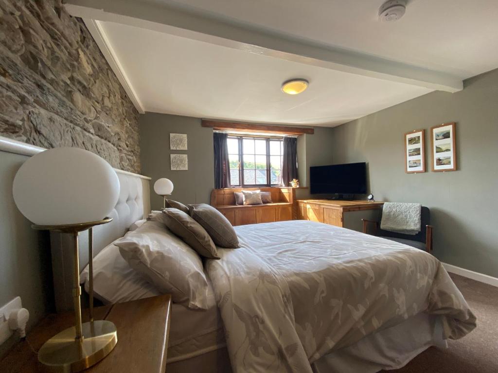 a bedroom with a bed and a stone wall at Tom's of Tregaron in Tregaron