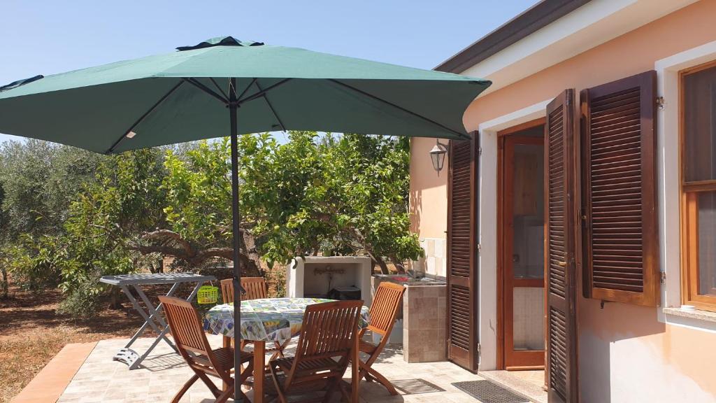een tafel en stoelen met een groene parasol op een patio bij CASA VACANZE DA NONNA MELA in Alghero