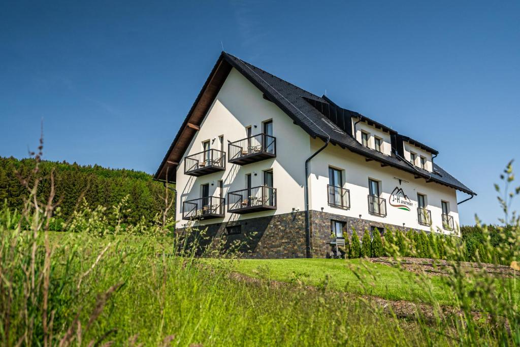 a large white house with a black roof at J-H APARTMÁNY HORSKÝ RESORT BUKOVÁ HORA - 100 m od LANOVKY in Červená Voda