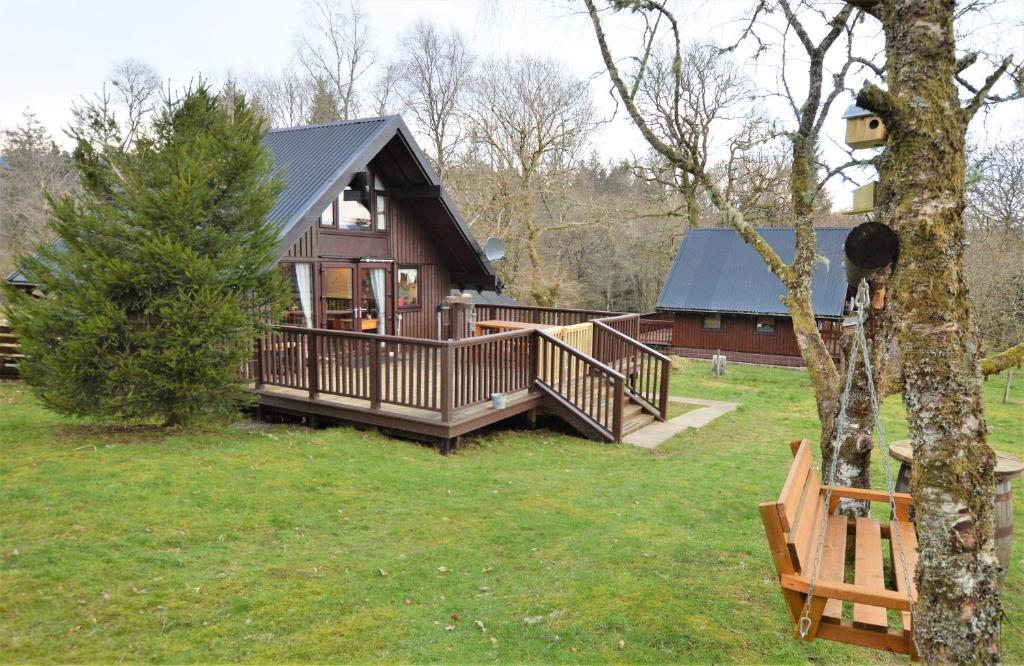 uma pequena casa com um alpendre e um deque em Iona Lodge em Dalavich