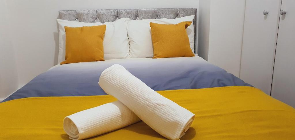 een bed met gele en blauwe lakens en gele kussens bij Marahomes in Bushey