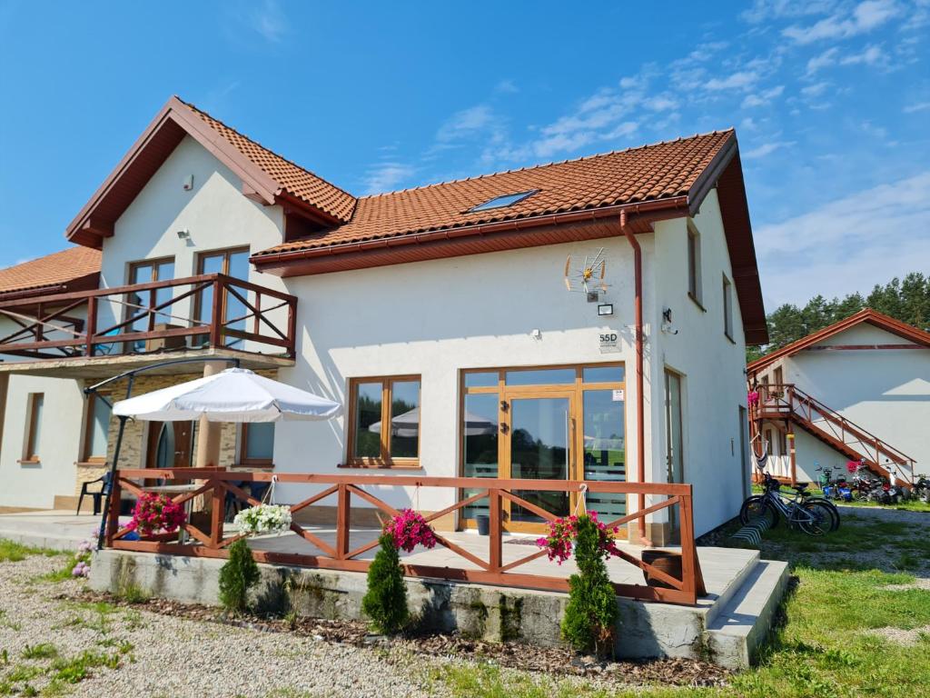 a small white house with a wooden deck at Chill Out Wygryny in Ruciane-Nida