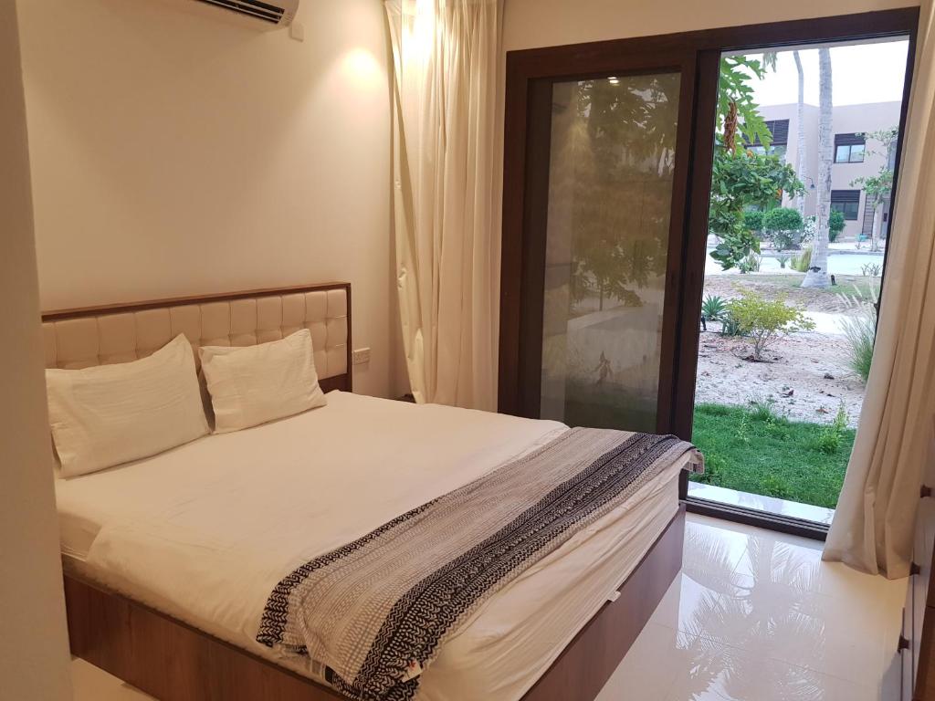a bedroom with a bed and a large window at Royal Hawana Apartment salalah in Salalah