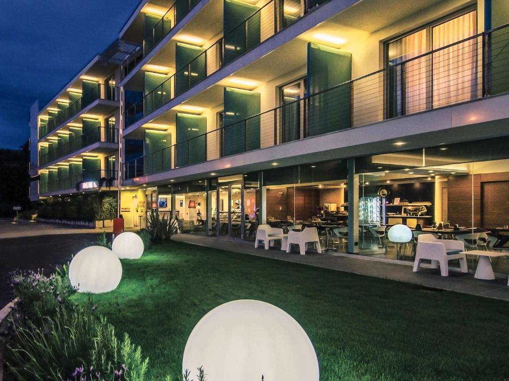 Hotel Viareggio في فياريجيو: مبنى به ساحة بها طاولات وكراسي بيضاء