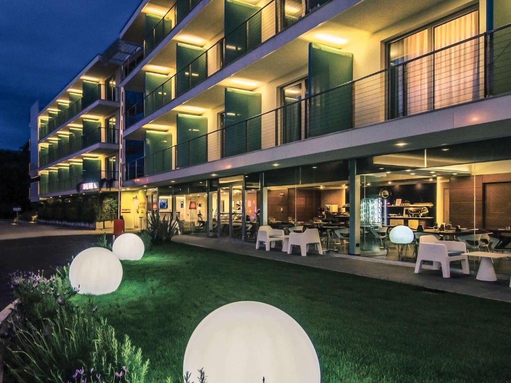 a building with a yard with white tables and chairs at Hotel Viareggio in Viareggio