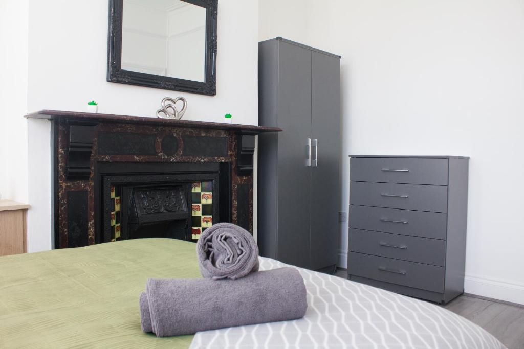 a bedroom with a bed with a headboard and a fireplace at Boaler House, modern 4 Bed House with parking Sleeps 8 in Liverpool