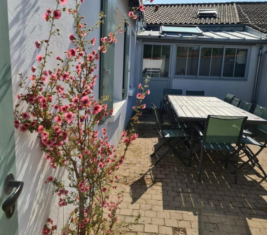 une table et des chaises sur une terrasse ornée de fleurs roses dans l'établissement Villa Babeth by Nuits au Port, à La Rochelle