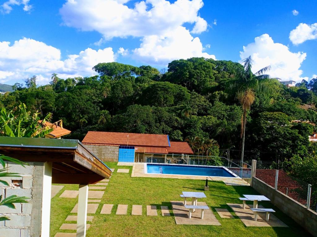 a backyard with a swimming pool and trees at Escondidinho da Serra in Serra Negra