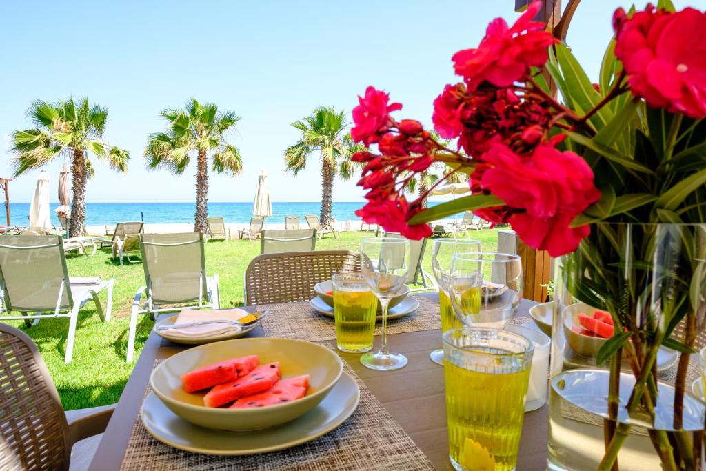 a table with a bowl of fruit and flowers on the beach at Pebble Beach Apartment in Voroklini