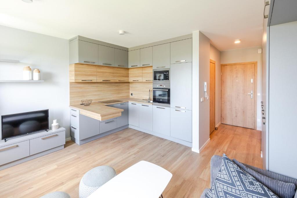 a kitchen with white cabinets and a tv in a room at Apartment Natura Vision in Opole