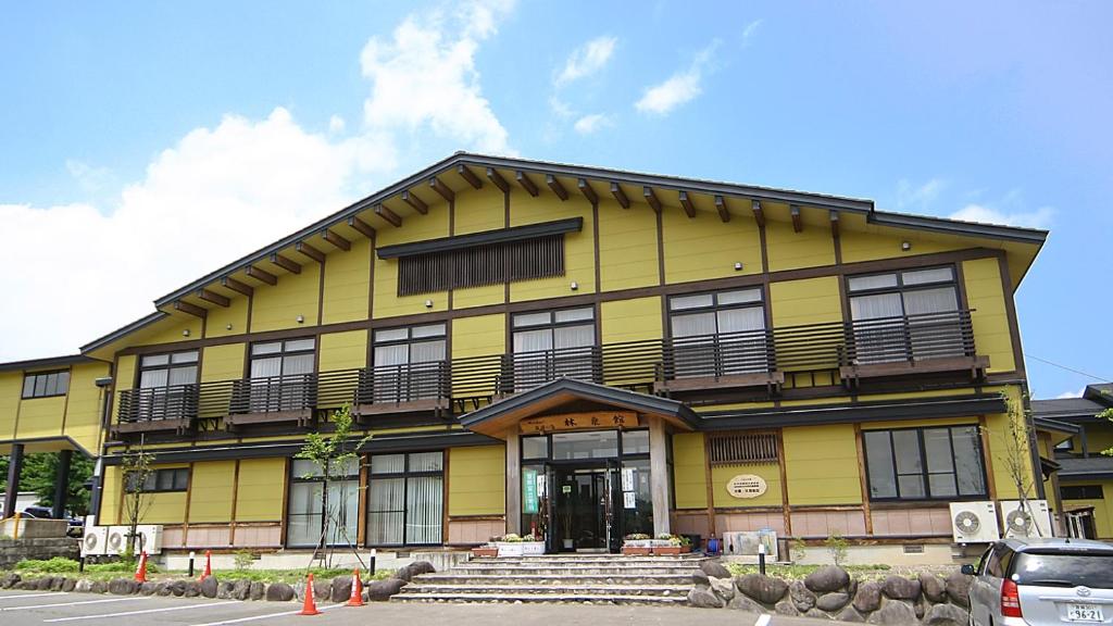 un edificio amarillo con porche y escaleras delante en Tabinoyado Yakurai Rinsenkan en Osaki