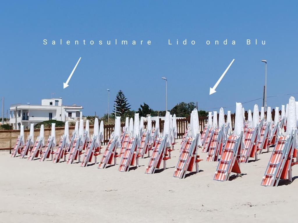uma fila de cadeiras de praia sentadas na praia em SalentosulMare em Marina di Lizzano
