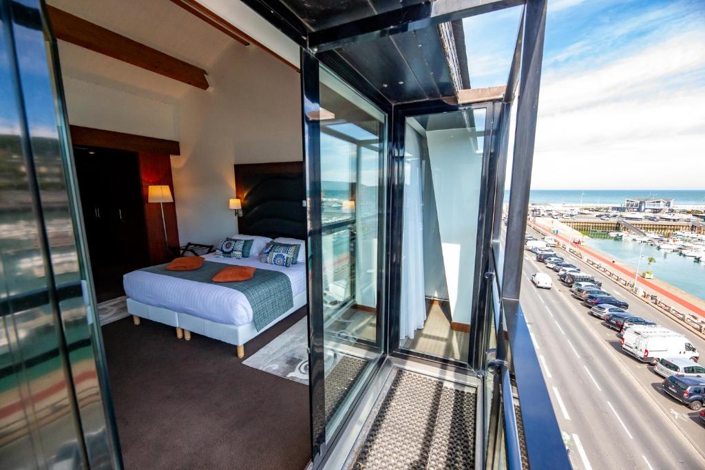 a hotel room with a bed and a view of a highway at Hotel Le Grand Pavois in Fécamp