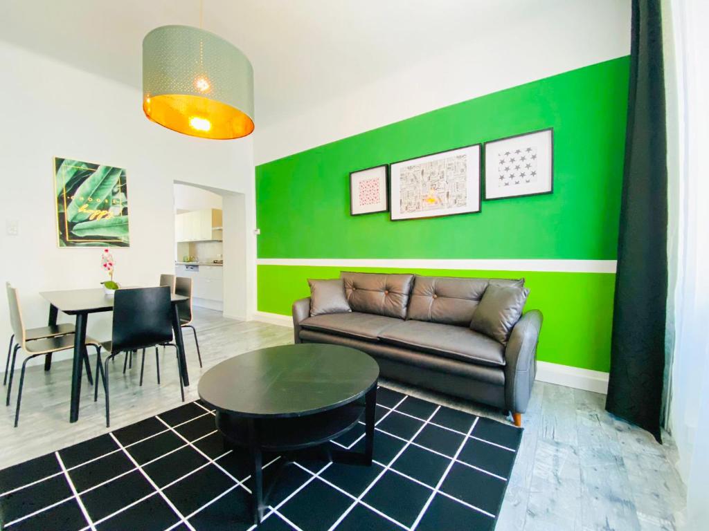 ein Wohnzimmer mit einem Sofa und einer grünen Wand in der Unterkunft Highlight Suite Donaustadt in Wien