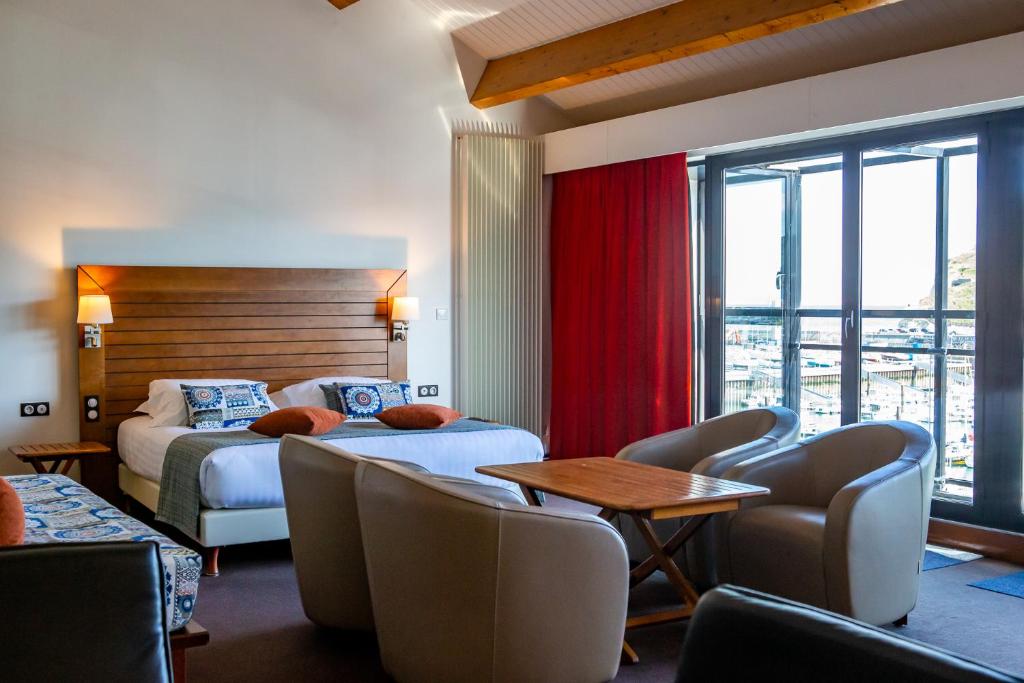 a hotel room with two beds and a table and chairs at Hotel Le Grand Pavois in Fécamp