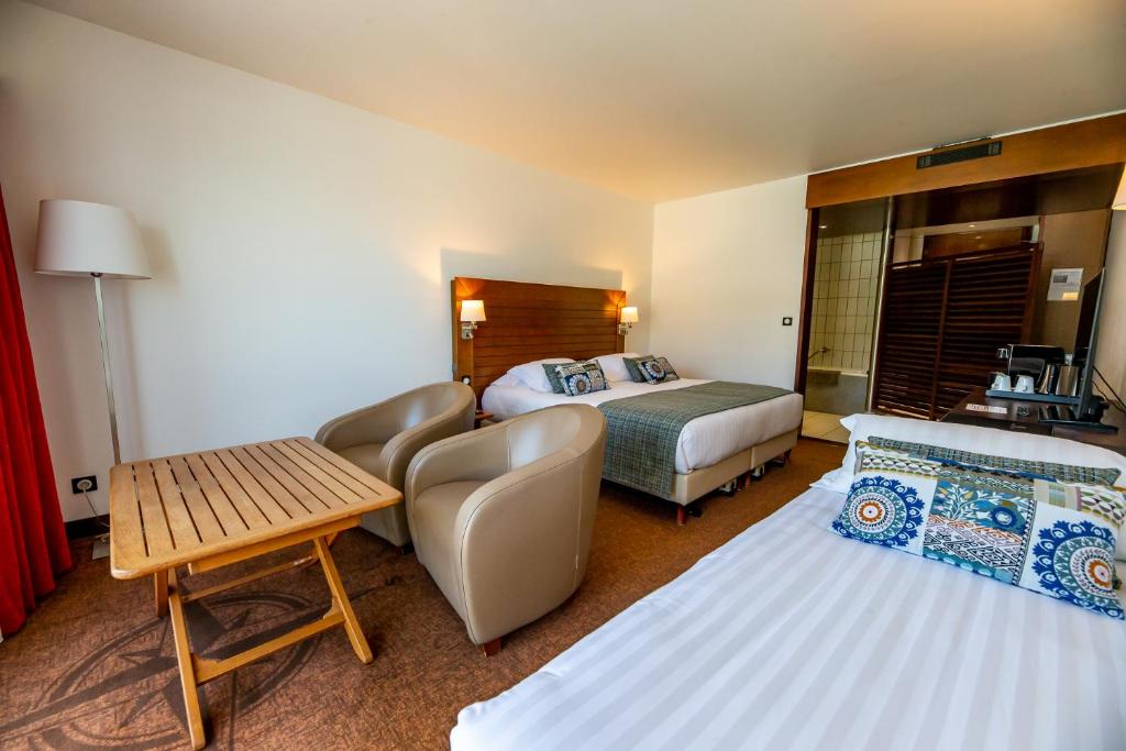 a hotel room with two beds and a couch and a table at Hotel Le Grand Pavois in Fécamp