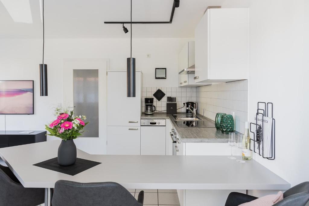 uma cozinha branca com um vaso de flores sobre uma mesa em Ferienwohnung im Fischerhaus em Nonnenhorn