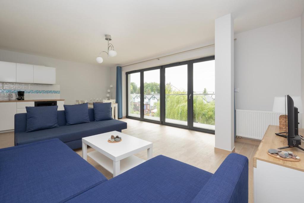 ein Wohnzimmer mit einem blauen Sofa und einem Tisch in der Unterkunft Jantar Apartamenty Siedem Wysp in Sianożęty