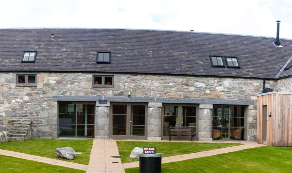 a stone building with windows and a yard at Hideaway Lodge in Kingussie