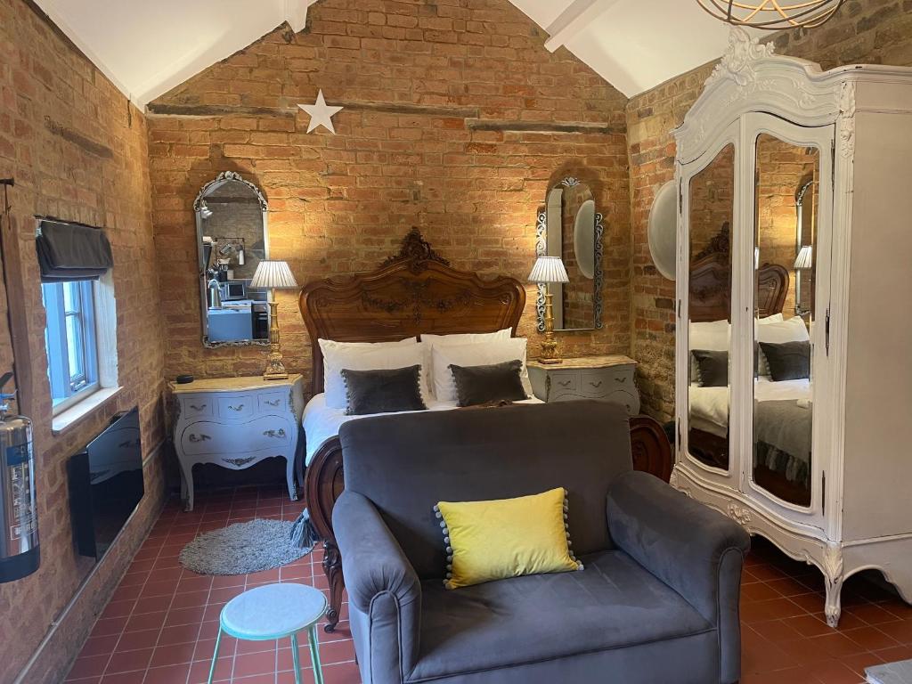 - une chambre avec un lit et un canapé dans l'établissement Topiary Barn - Stylish Accommodation in Rutland, à Uppingham