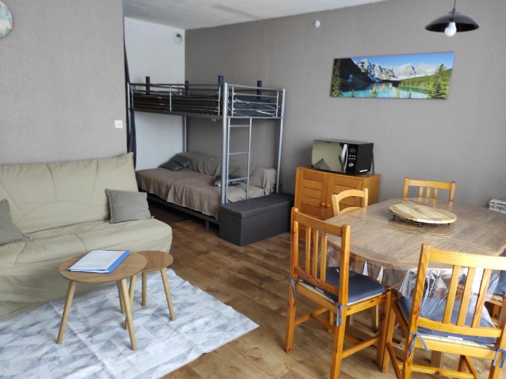 ein Wohnzimmer mit einem Sofa, einem Tisch und einem Bett in der Unterkunft La Géla, studio cabine pieds de pistes in Aragnouet