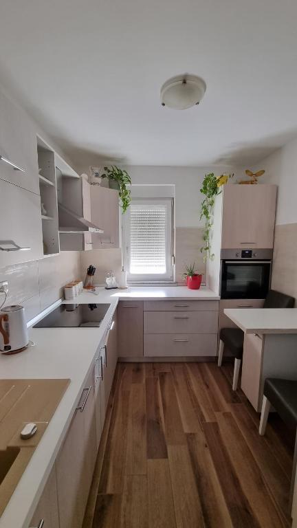 een keuken met witte kasten en een houten vloer bij Apartman Ori in Umag