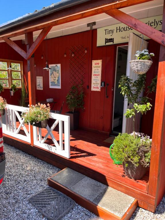 Tiny House Marielyst في Bøtø By: مبنى احمر فيه نباتات خزف خارجه