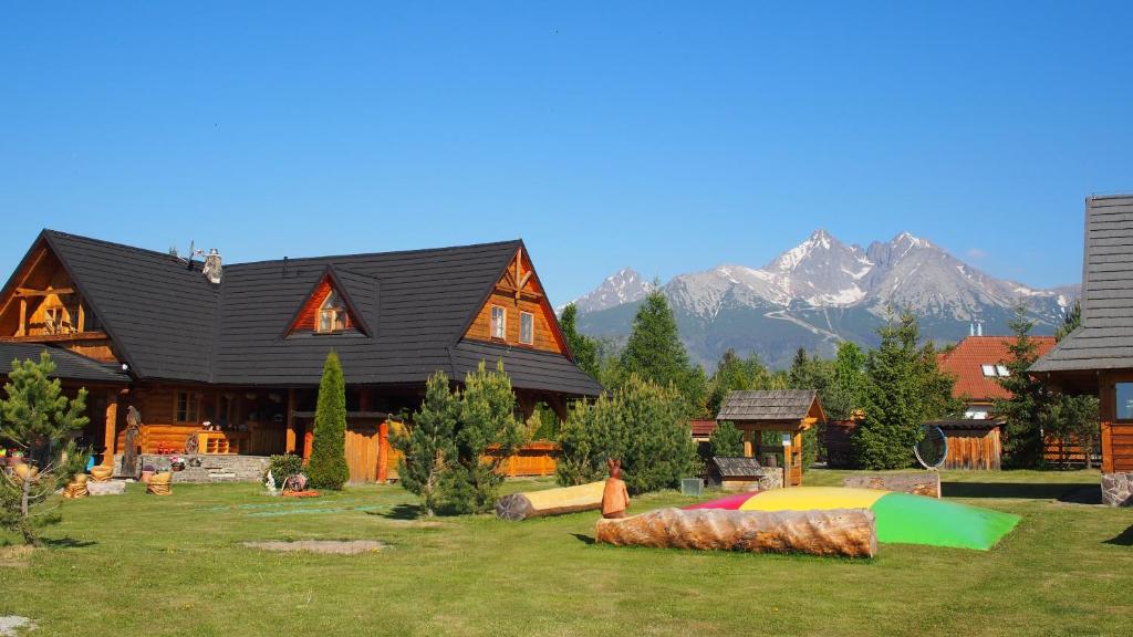a large log cabin with mountains in the background at Chaty Rozprávkovo in Vysoke Tatry - Tatranska Lomnica.