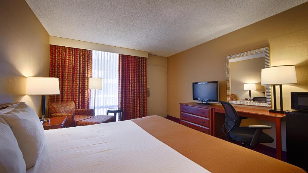 a hotel room with a bed and a desk and a television at West Gate Inn Nyack in Nyack