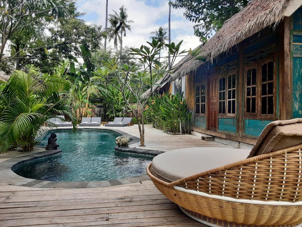 Musa Bintang Villas and Bungalows Gili Air في غيلي آير: حمام سباحة مع كرسي الخوص بجوار منزل