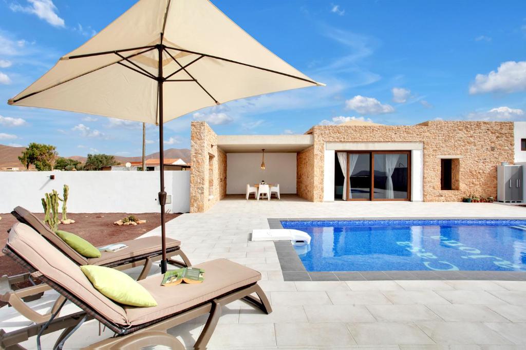 een patio met een parasol en een zwembad bij Casa Rural Sajoná in Tiscamanita