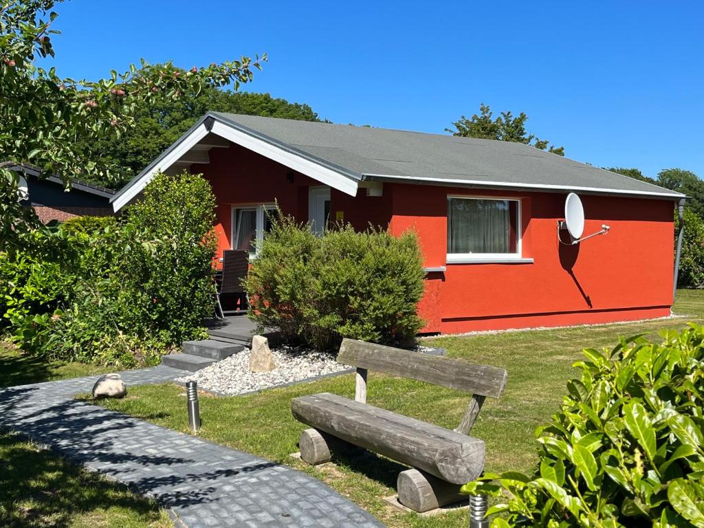 una casa roja con un banco delante en Ferienanlage Bullerbü, en Lohme