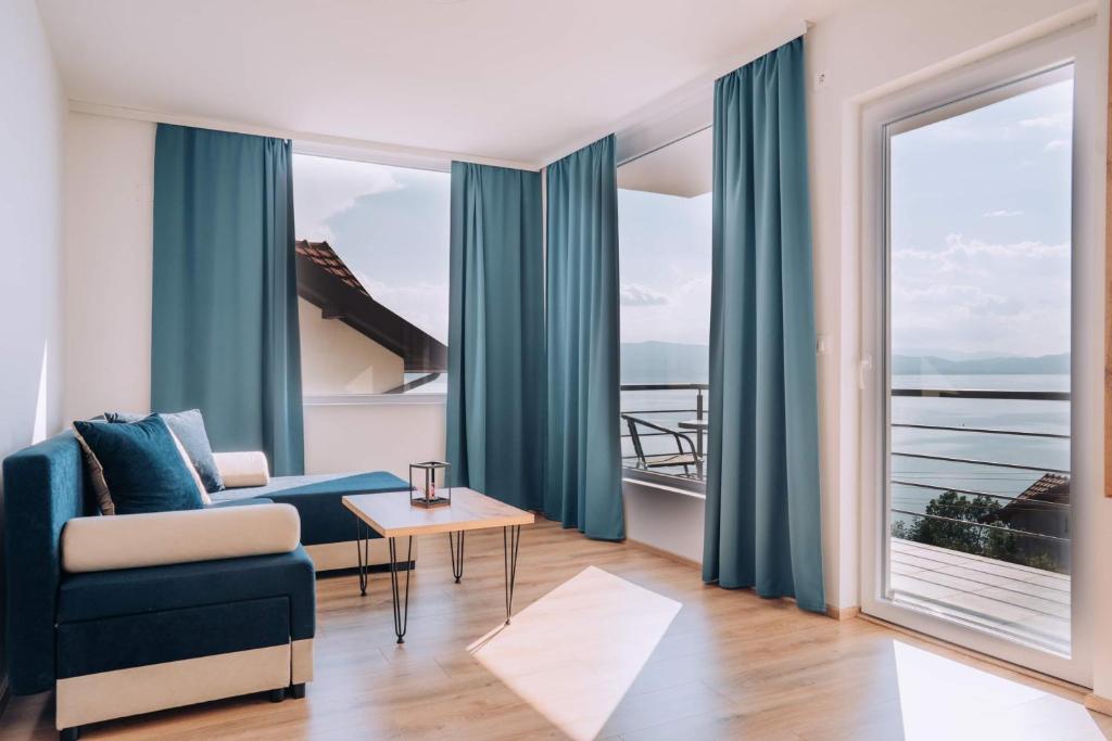 a living room with a blue couch and a large window at VILA PUPA with Lake view - Elešec in Ohrid