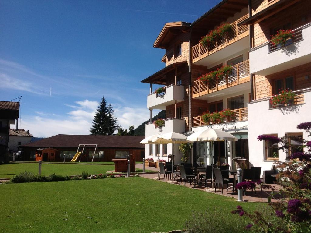 a building with chairs and umbrellas in a yard at Residence Nele in Ziano di Fiemme