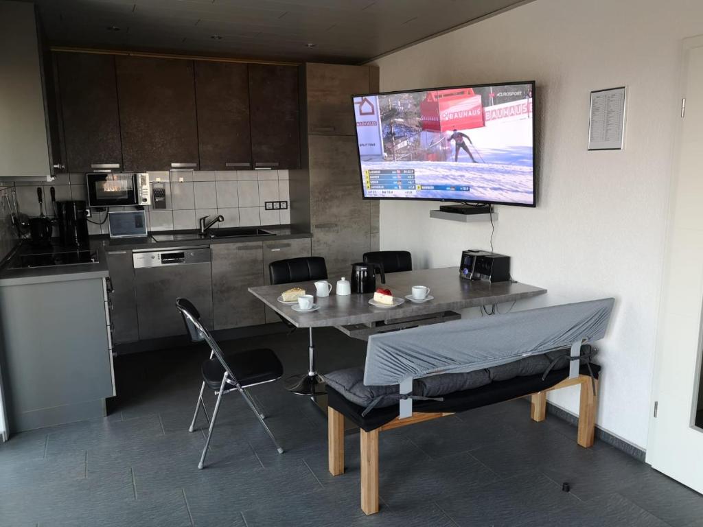 una cucina con tavolo, sedie e TV a schermo piatto di Ferienhaus Ausblick Am Eichenberg a Blankenburg