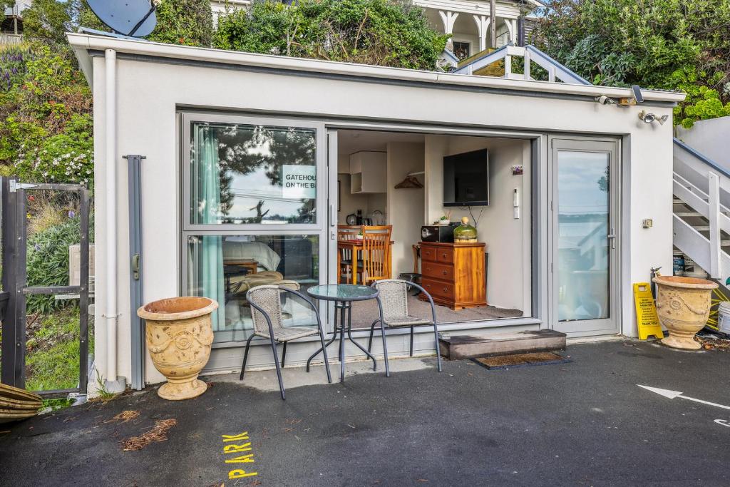 uma pequena casa branca com uma mesa e cadeiras em Gatehouse on the Bay - Christchurch Holiday Unit em Christchurch