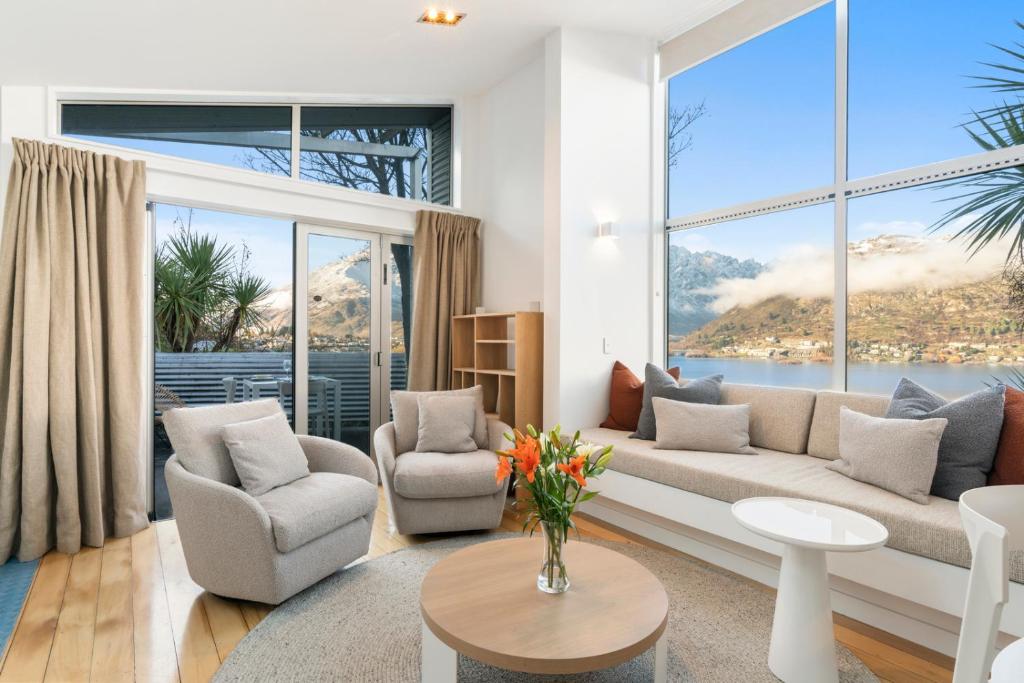 a living room with a couch and chairs and a large window at A Stunning Stay - Queenstown Holiday Home in Queenstown