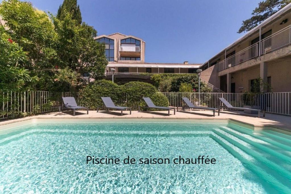 a swimming pool with chairs next to a building at Hotel Cantosorgue in L'Isle-sur-la-Sorgue