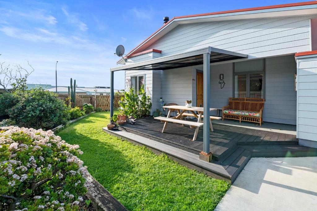 新普利茅斯的住宿－Ekhaya - New Plymouth Holiday Home，一间白色的小房子,在庭院里设有野餐桌