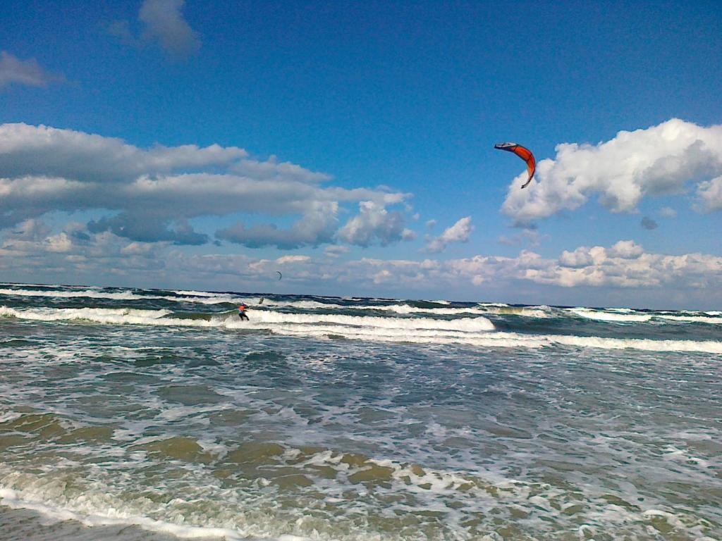 a person is flying a kite in the ocean at Domki PrzystańTu in Jastarnia