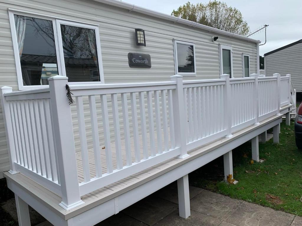 una cerca blanca de vinilo en una casa pequeña en New 2 bed holiday home with decking in Rockley Park Dorset near the sea, en Lytchett Minster