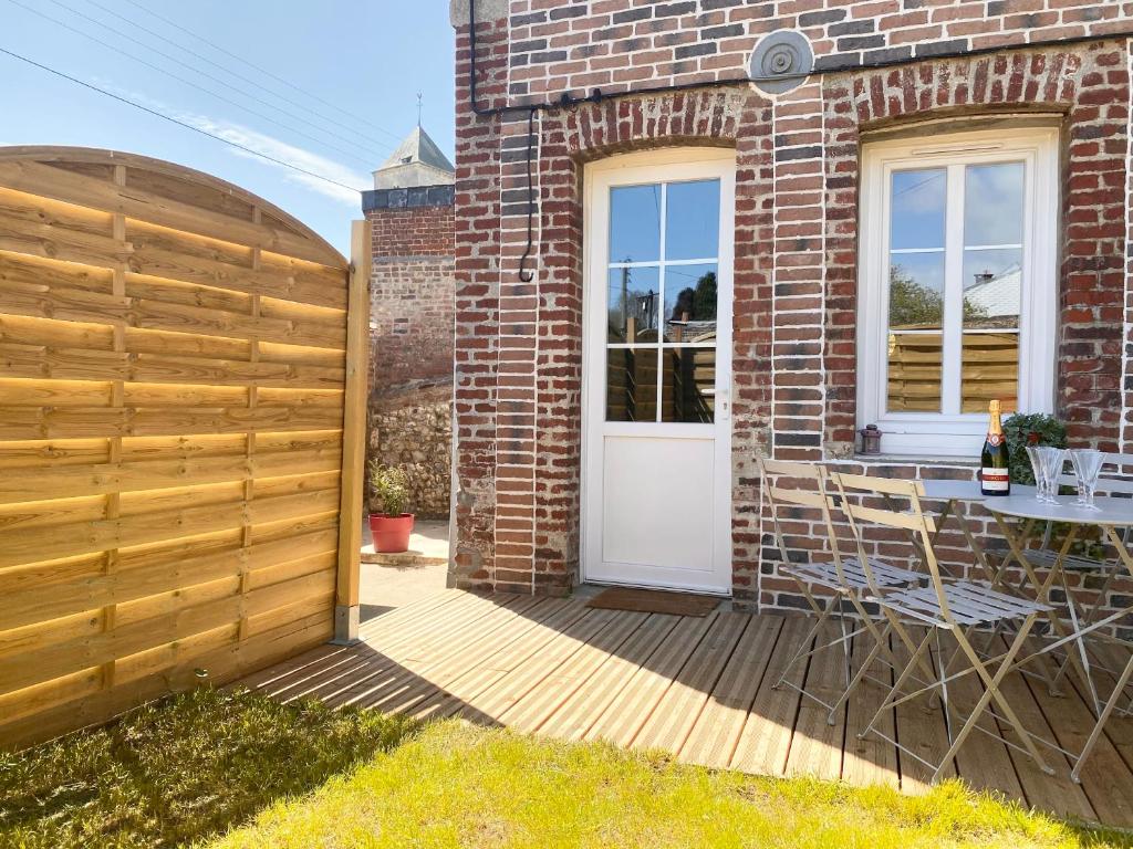 una recinzione di legno accanto a una casa di mattoni con porta bianca di La Tourmaline - Etretat a Étretat