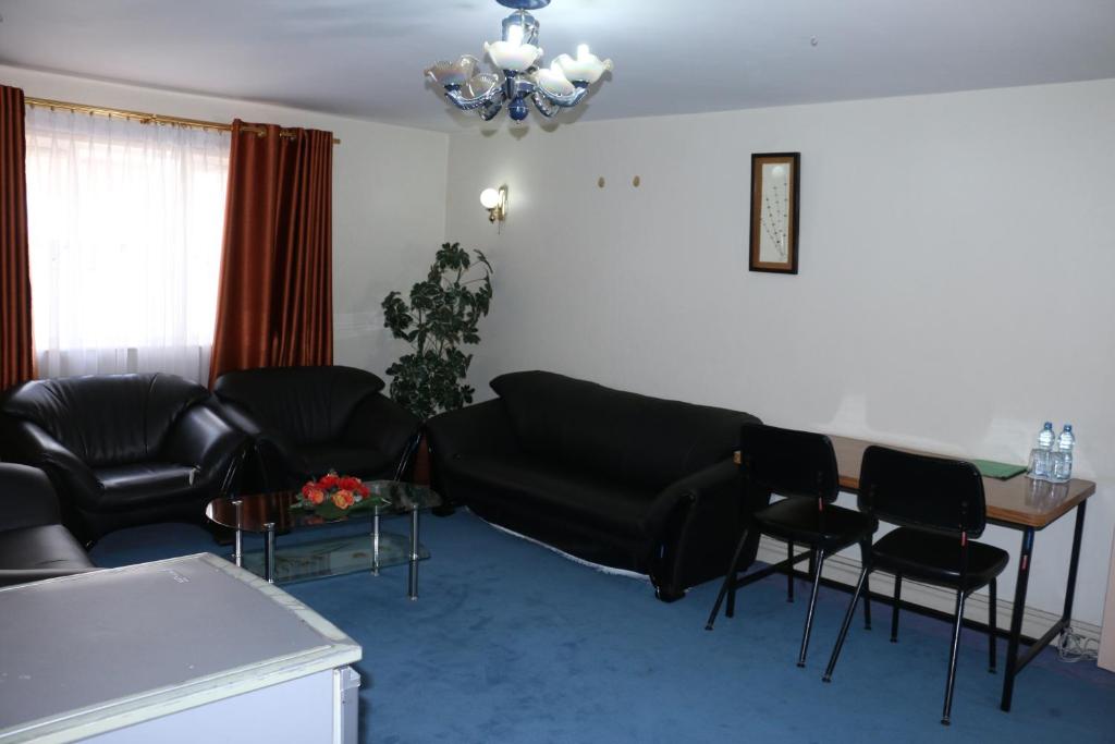 sala de estar con muebles negros, mesa y sillas en Adventist LMS Guest House & Conference Centre en Nairobi