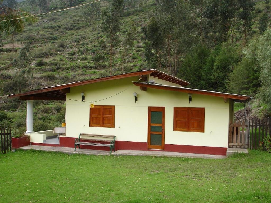 una pequeña casa con un banco en un patio en Swiss Chalet with Private Kitchen near Lima en Canta