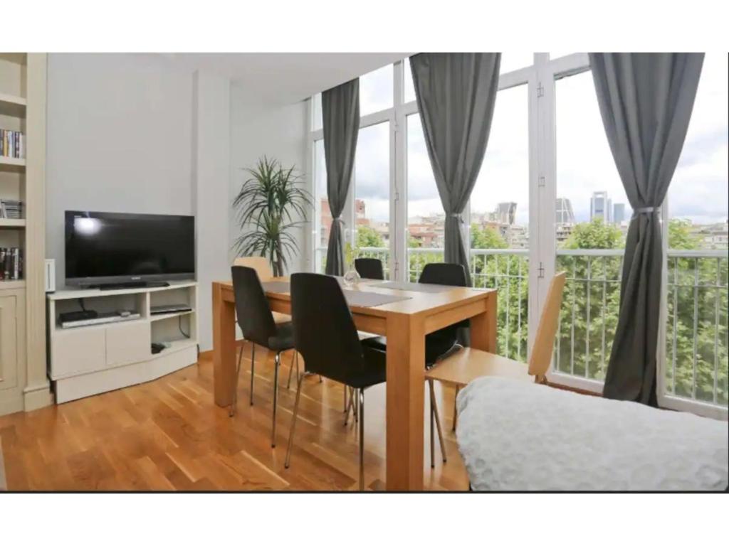 Madrid Views Apartment في مدريد: غرفة معيشة مع طاولة طعام وكراسي