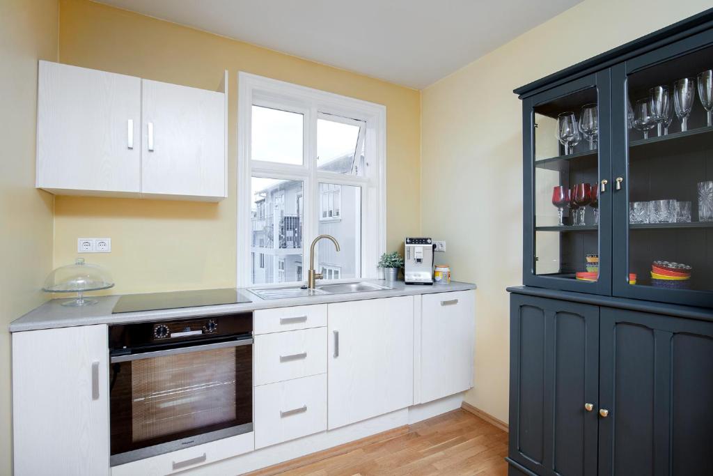 cocina con armarios blancos, fregadero y ventana en Live as Locals Apartments, en Reikiavik