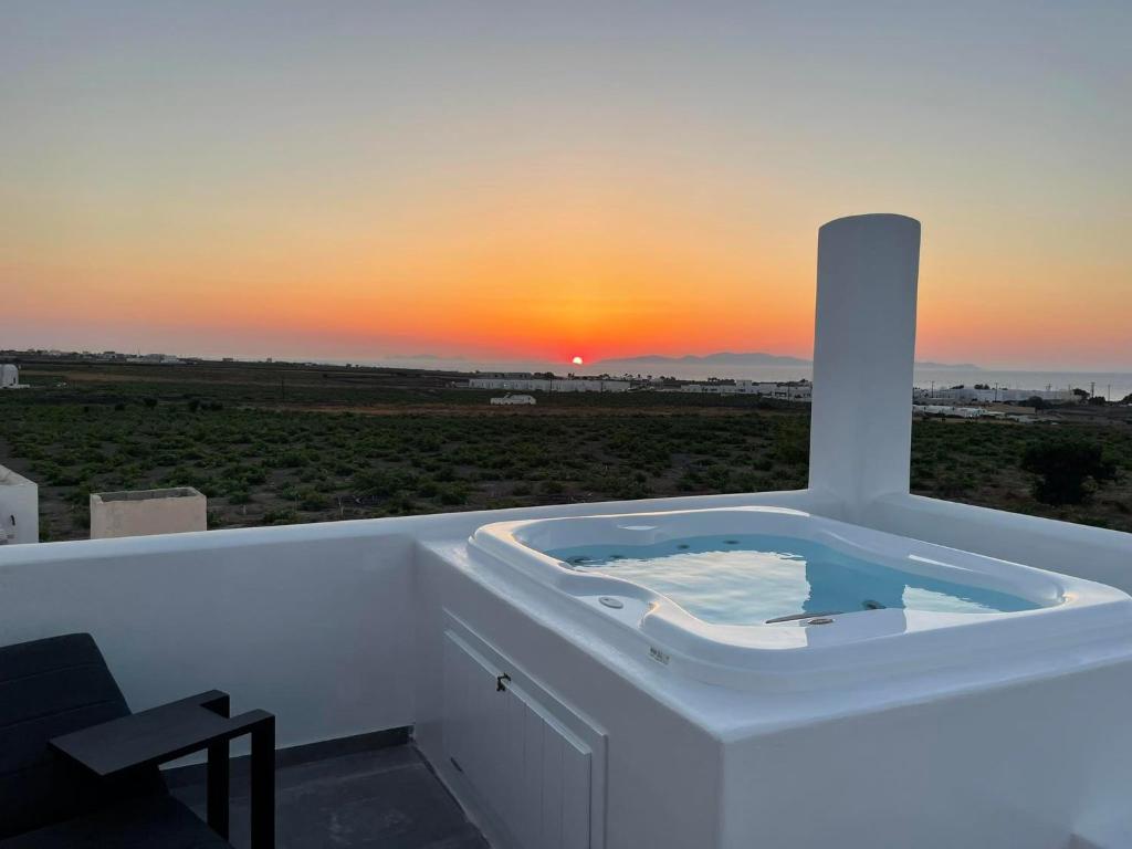 a bath tub with a sunset in the background at Anemi Vine Villas in Foinikiá
