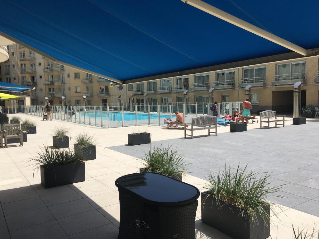een patio met planten en een zwembad in een gebouw bij Studio 4 pers met Frontaal Zeezicht & privé zwembad Oostende in Oostende