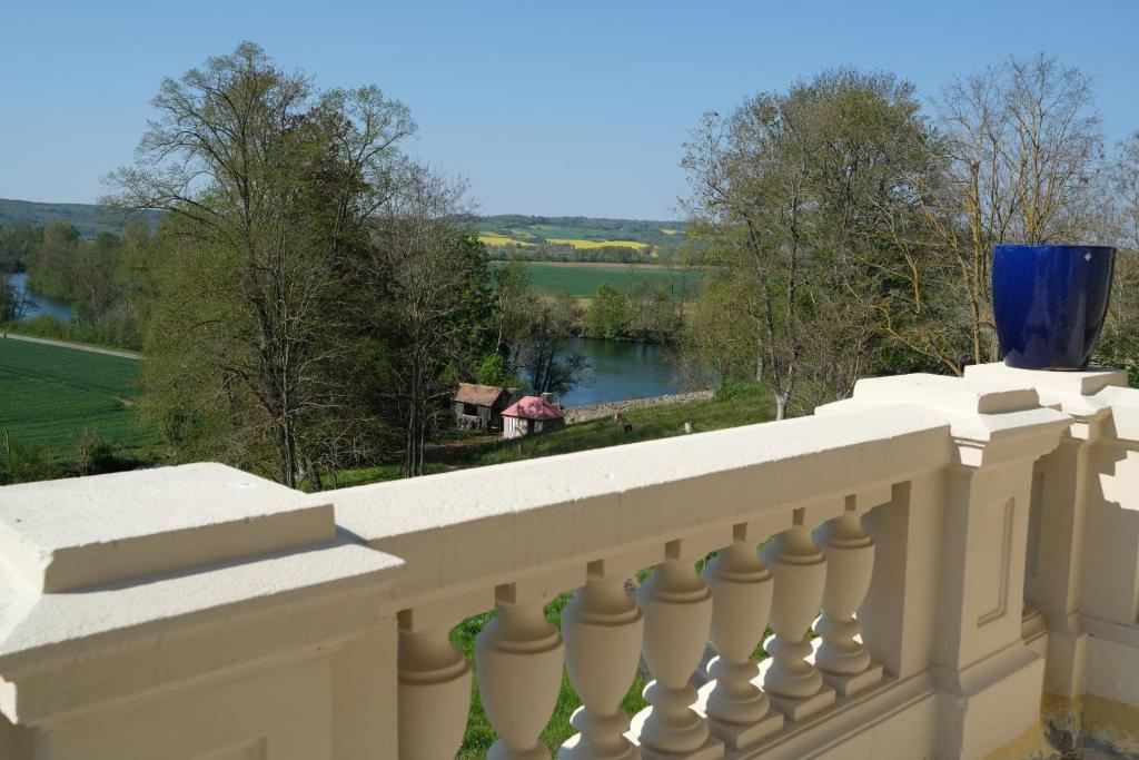 Un balcón blanco con un jarrón azul. en Grand-Varennes, en Serbonnes
